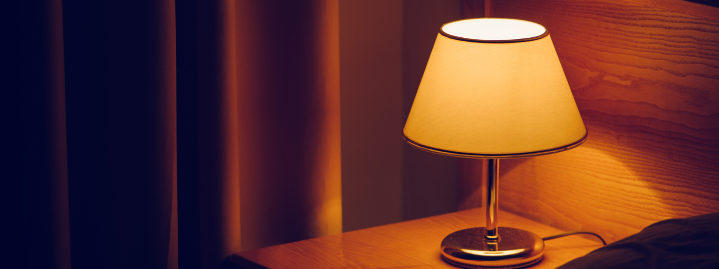 A lamp on a nightstand, turned on