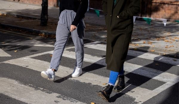 Two people walking side by side across the road on a zebra crossing