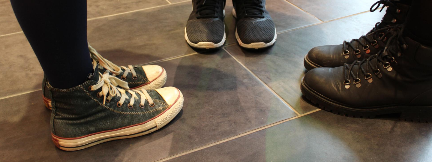 Three pairs of shoes zoomed in on a tile floor