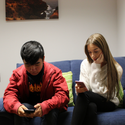 Right-image-1 Two young people sitting on a couch on their phones