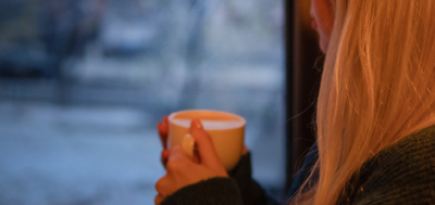 Information Close up of a woman holding a mug looking outside a window
