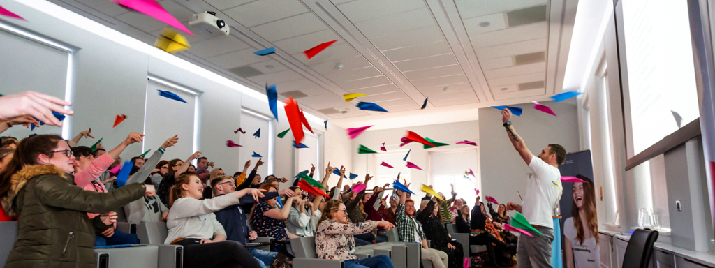 a group of young people at a training day throwing paper airplanes