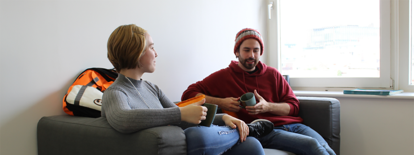 young man and woman sitting on sofa drinking coffee
