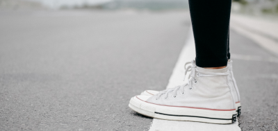 Information picture of a person wearing converse runners standing on a white painted line