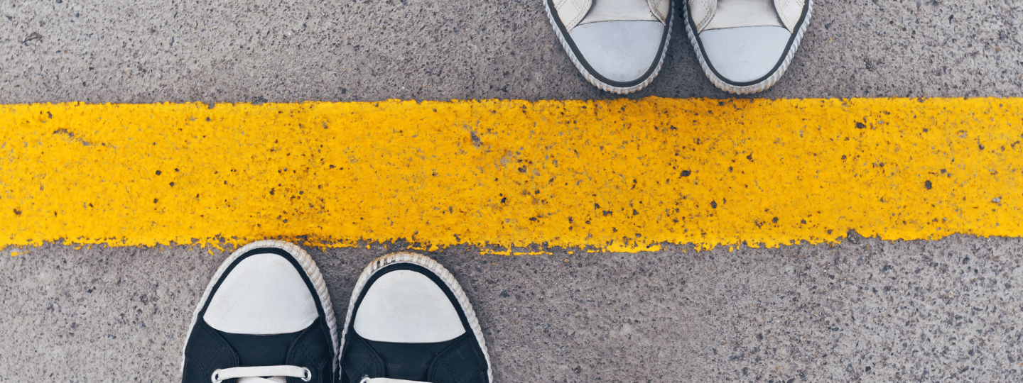 A image of two pairs of shoes standing either side of a yellow line