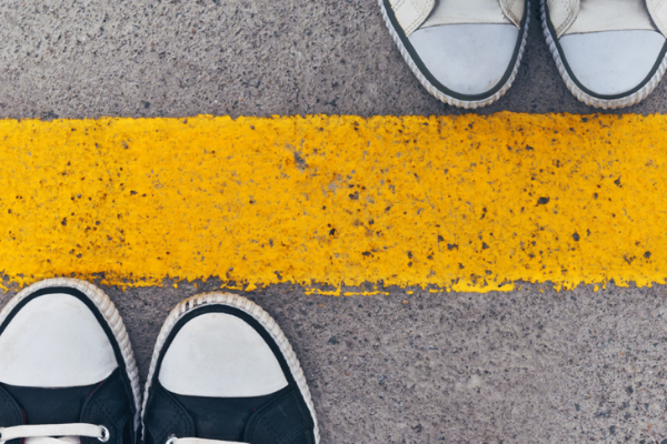 A image of two pairs of shoes standing either side of a yellow line for managing feelings