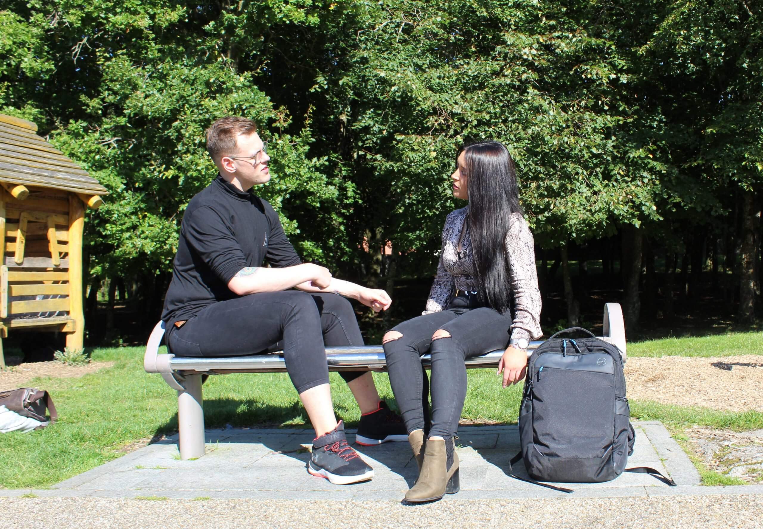 Two friends chatting Two young people chatting on a park bench