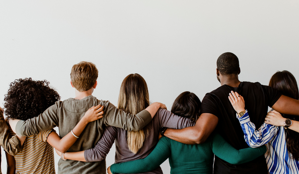 back view of diverse people with their arms around each other