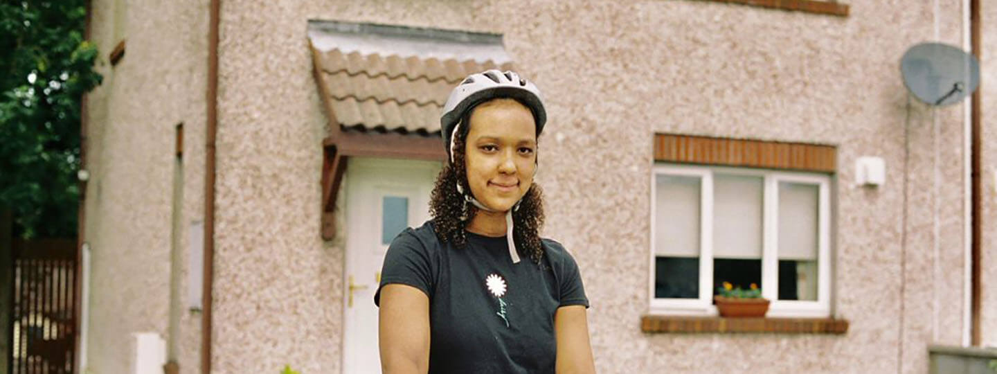 Amina, one of our volunteers in front of her house with cycling helmett