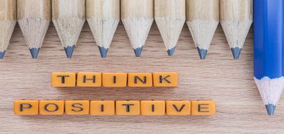 Information Think positive spelt out in blocks on table with group of pencils