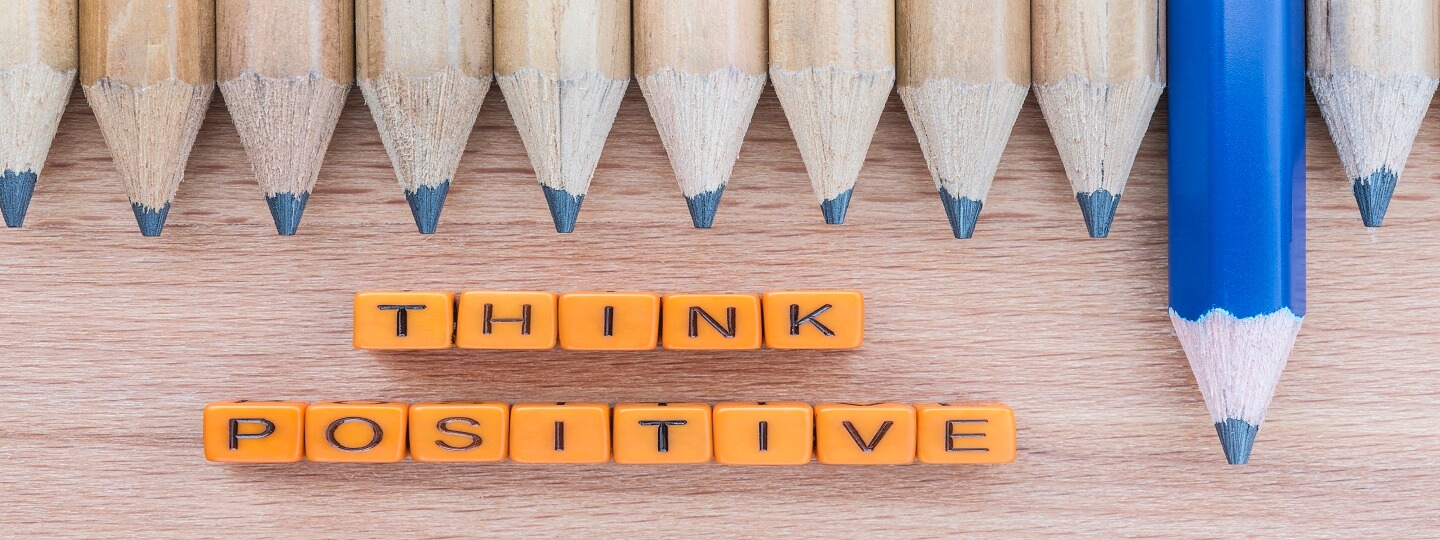 Think positive spelt out in blocks on table with group of pencils