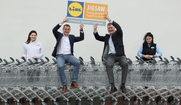 CEO from Lidl and Jigsaw sit on trolleys holding signs