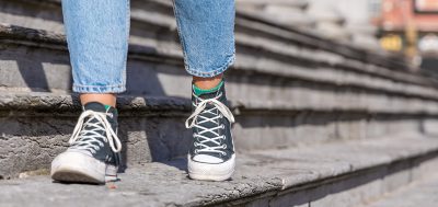feet wearing converse walking along old grey steps