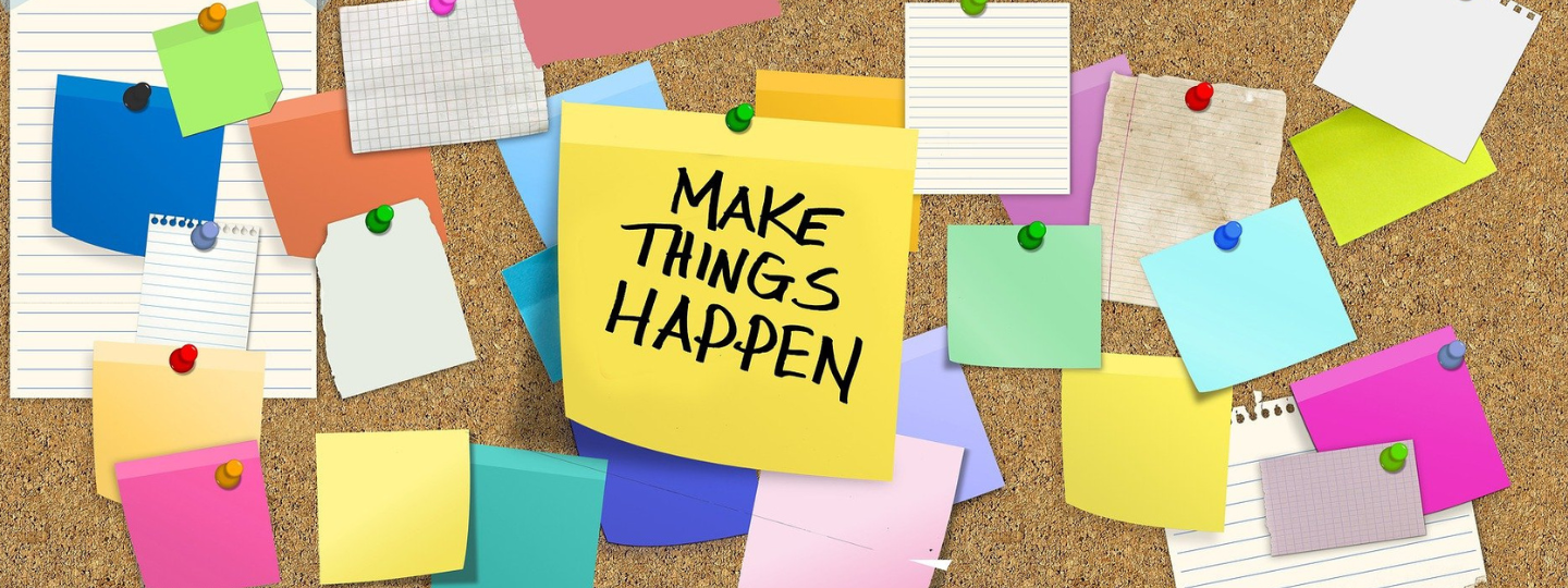 post-it with make things happen written on noticeboard (1)