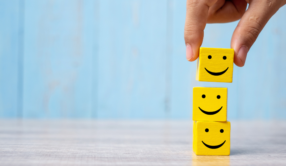 three wooden cubes with smiley faces stacked on top of each other