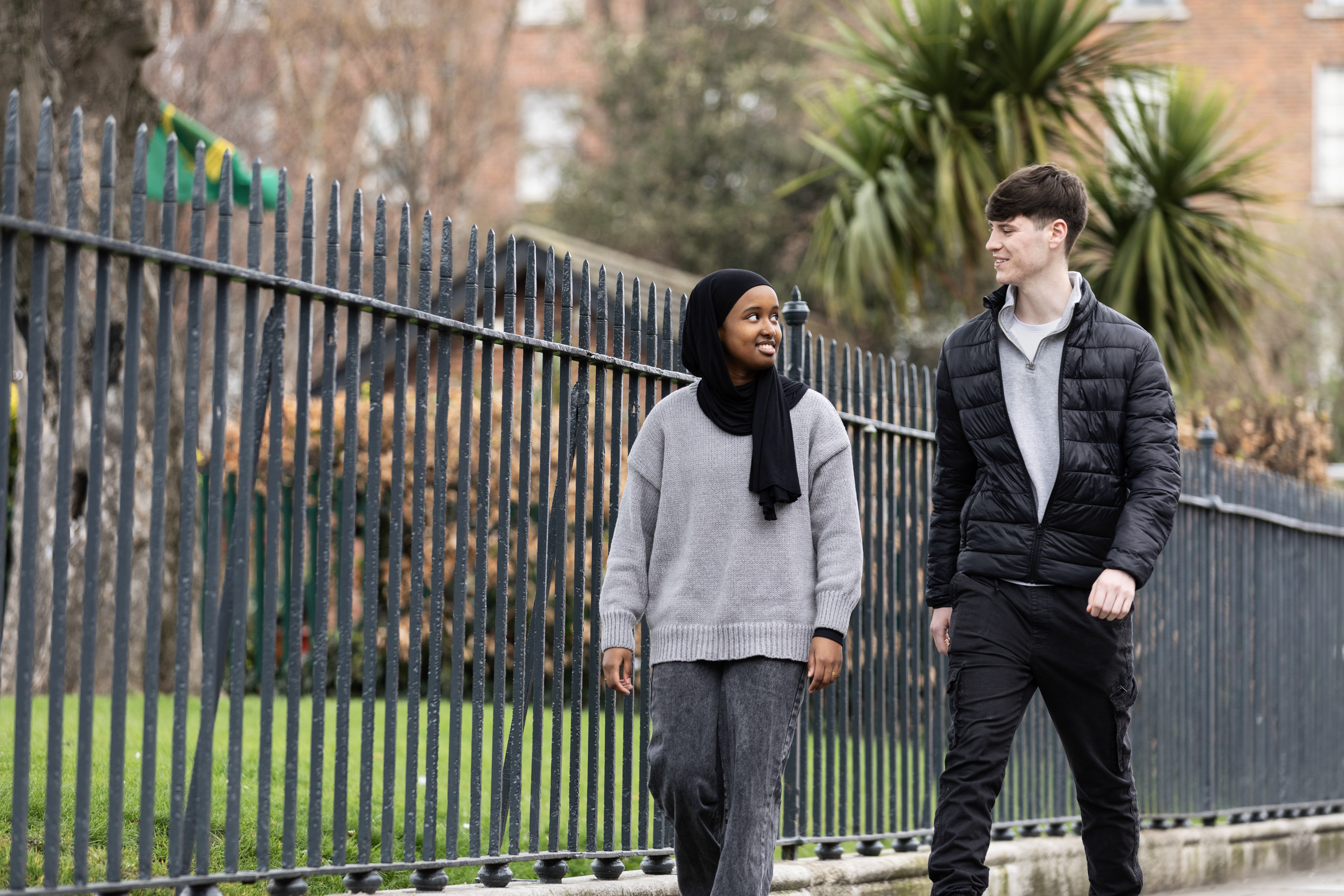 young man and young woman walking together near park
