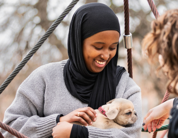 young woman smiling holding a small puppy
